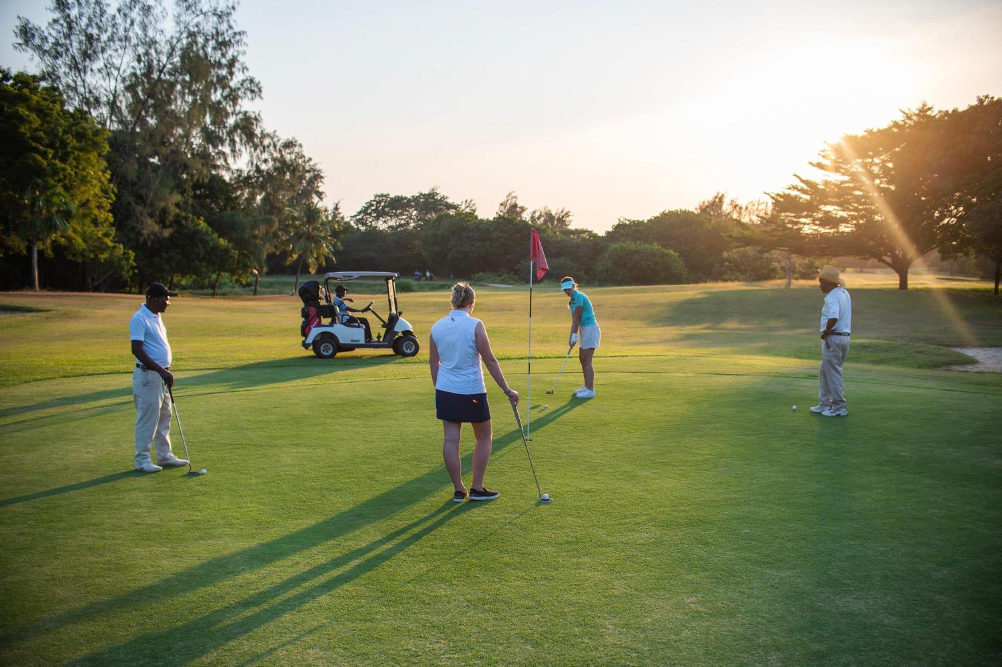 Diamonds Leisure Beach & Golf Resort Diani Beach Exterior photo Golfers putting on the 18th green at the Royal Pines Resort
